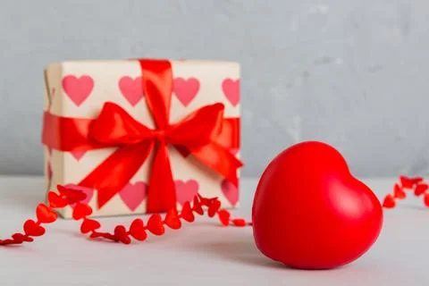 Gift box with red bow and red heart on colored background. Perspective view.  Stock Photos