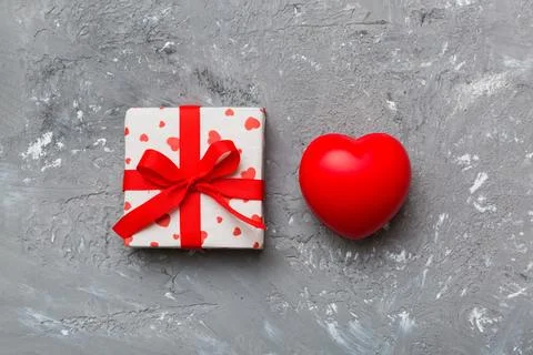 Gift box with red bow and red heart on colored background . Top view. Flat la Stock Photos