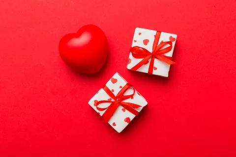 Gift box with red bow and red heart on colored background . Top view. Flat la Stock Photos