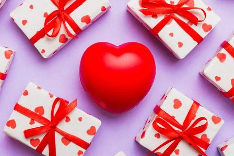 Gift box with red bow and red heart on colored background . Top view. Flat la Stock Photos