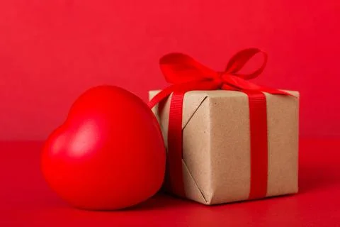 Gift box with red bow and red heart on colored background. Perspective view.. Stock Photos