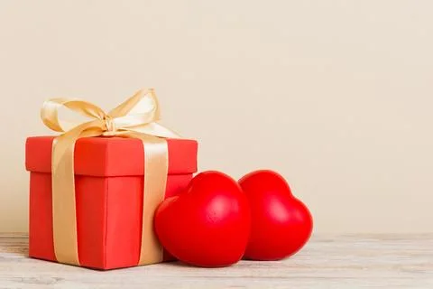 Gift box with red bow and red heart on colored background. Perspective view.. Stock Photos