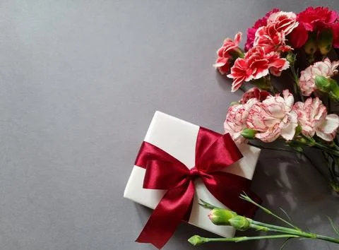 Gift box with a red bow and a bouquet of flowers Stock Photos