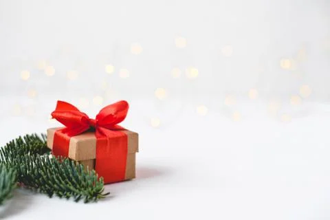 Gift box with a red bow on a background of blurred lights garland. Stock Photos