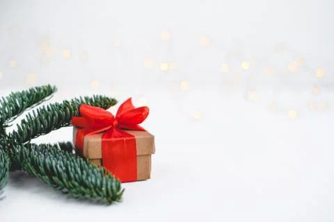 Gift box with a red bow on a background of blurred lights garland. Stock Photos