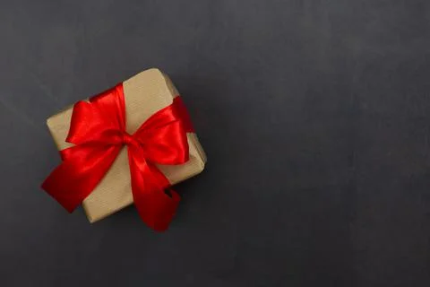Gift box with red bow on a black background. Festive background. Copy space. Stock Photos