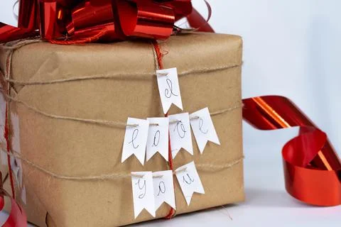 Gift box with red bow, "I love you" lettering, white background Stock Photos