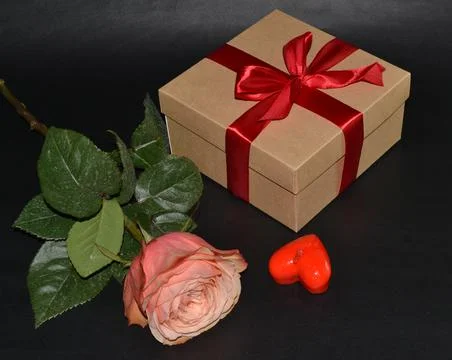 Gift box with red bow, pink rose and aroma candles on a black background Foto stock