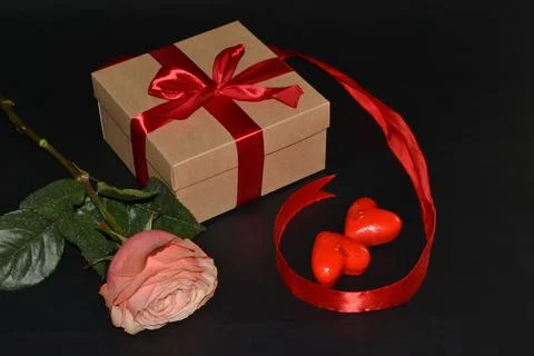 Gift box with red bow, pink rose and aroma candles on a dark background Foto stock