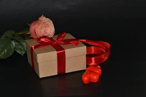 Gift box with red bow, pink rose and aroma candles on a dark background Foto stock