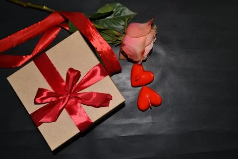 Gift box with red bow, pink rose and aroma candles on a dark background. Top  Foto stock