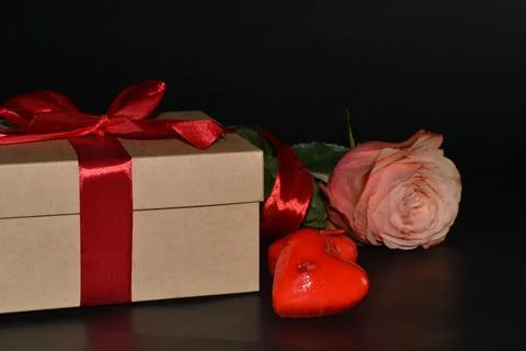 Gift box with red bow, pink rose and aroma candles on a dark background Foto stock