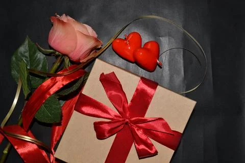 Gift box with red bow, pink rose and aroma candles on a dark background. Top  Foto stock