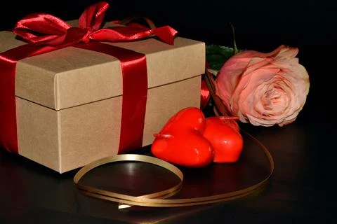 Gift box with red bow, pink rose with golden ribbon and aroma candles on a da Foto stock