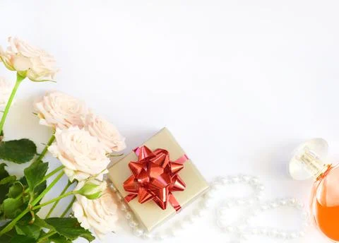 Gift box with red bow, pink roses, beads with perfume bottle on white backgro Stock Photos