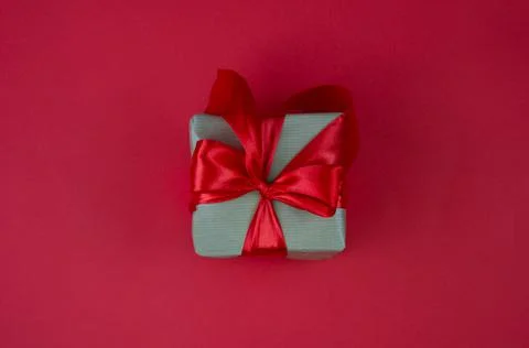 Gift box with red bow on red background. Festive background. Copy space. Stock Photos