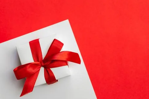 Gift box with a red bow on a red background, flat lay, copy space. Stock Photos