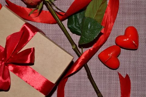 Gift box with a red bow, rose leaves and aroma candles white shape of heart.  Foto stock