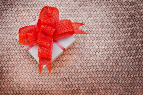 Gift box with a red bow on a straw background. Stock Photos