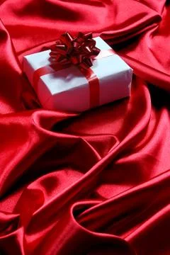 Gift box on red satin background Stock Photos