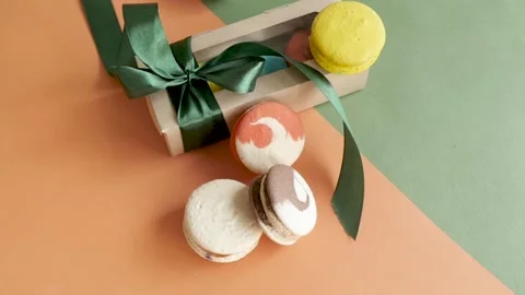 Gift box with ribbon and inside macaroni comes in a frame on green and orange Stock-Footage 139529629