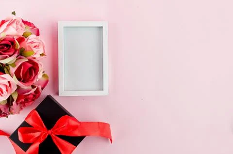 Gift box, roses and empty frame on a pink background Stock Photos