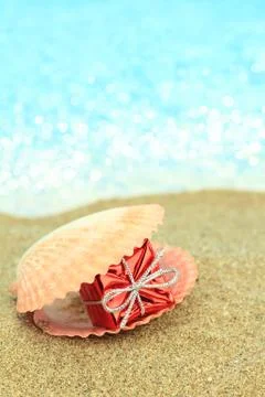 Gift box in a sea shell on the beach Stock Photos