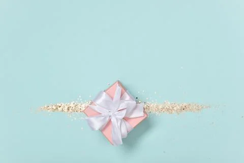Gift box with sequins on a blue background. Minimalism. Stock Photos