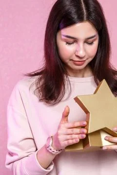 Gift box in the shape of a gold star in the hands of a young Asian girl. on a Stock Photos