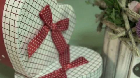 A gift box in the shape of a heart and a small bouquet of flowers Stock Footage 123684784