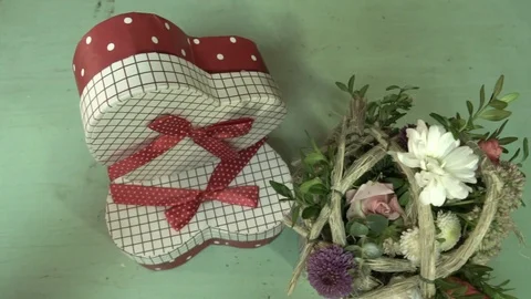 A gift box in the shape of a heart and a small bouquet of flowers Video stock 123684848