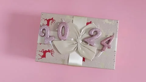 Gift box with shiny candles numbers 2024 on a pink background. Stock Footage 255675855