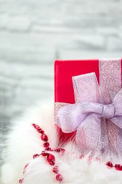 Gift box with silver bow in fluffy bag with red shiny beads Stock Photos