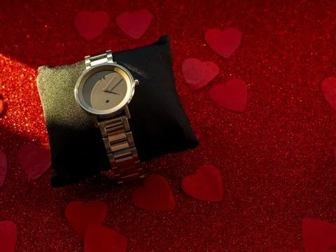 Gift box with silver watch is on red heart paper background Stock Photos