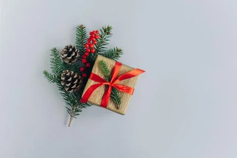 Gift box with spruce branches, cones and red berries on a gray background. .. Stock Photos