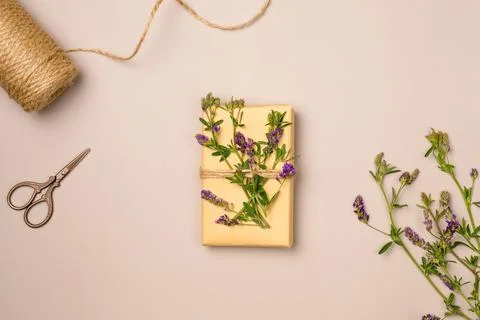 Gift box, string, scissors, flowers on beige background from above. Gift wr.. Stock Photos