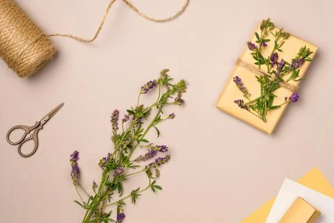 Gift box, string, scissors, flowers on beige background from above. Gift wr.. Stock Photos