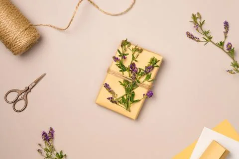 Gift box, string, scissors, flowers on beige background from above. Gift wr.. Stock Photos