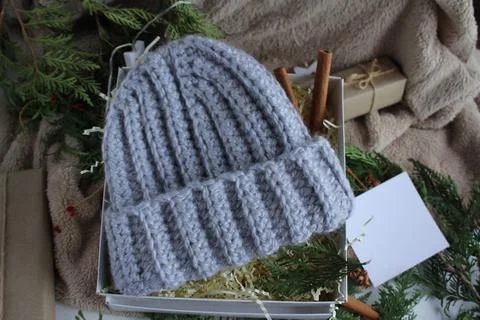 The gift box is on the table. In the box is a knitted gray hat. Gifts for the Stock Photos