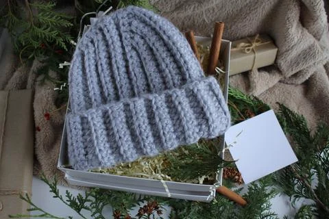 The gift box is on the table. In the box is a knitted gray hat. Gifts for the Stock Photos