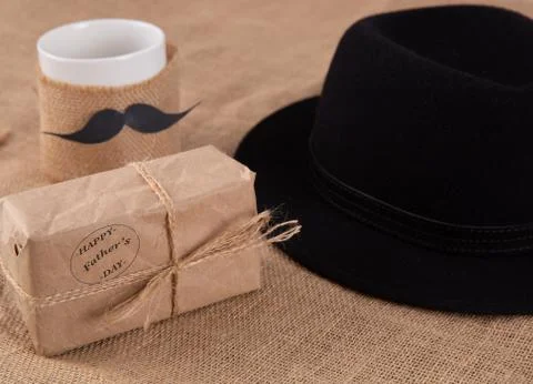 Gift box on the table. Next to a cup with a glued mustache. Foto stock