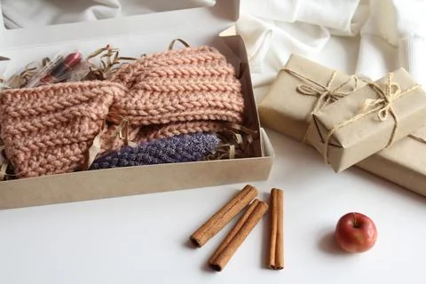 The gift box is on the table. There is a knitted bandage in the box. Gifts for Stock Photos
