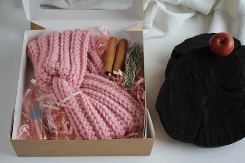 The gift box is on the table. There is a knitted bandage in the box. Gifts for Stock Photos