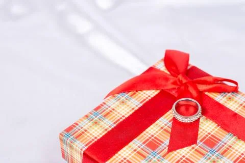 Gift box with wedding ring on it over white satin Stock Photos