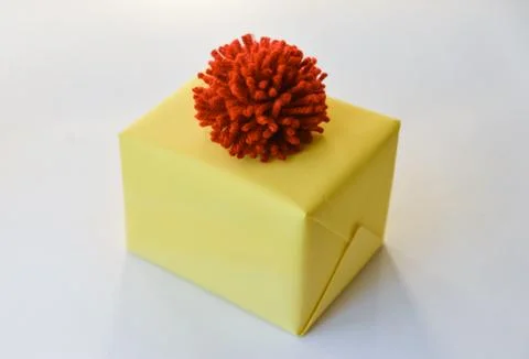 Gift box on a white background. winter holidays, pompom from threads, warm Stock Photos