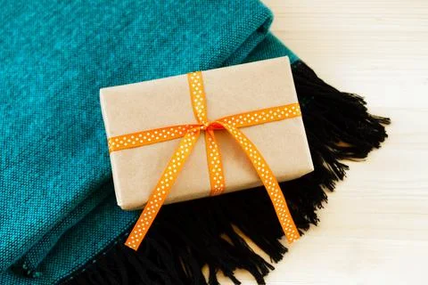 Gift box wrapped of craft paper and orange ribbon on a turquoise and black .. 写真素材