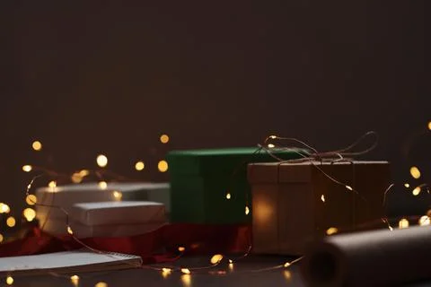 Gift boxes and festive packaging with christmas light on a table closeup Stock Photos