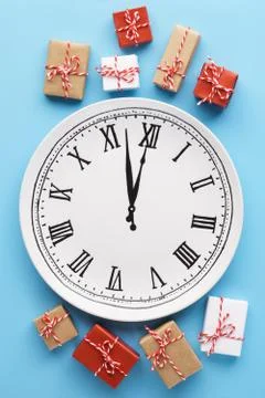 Gift boxes around a plate clock on light blue background. Stockfoto's
