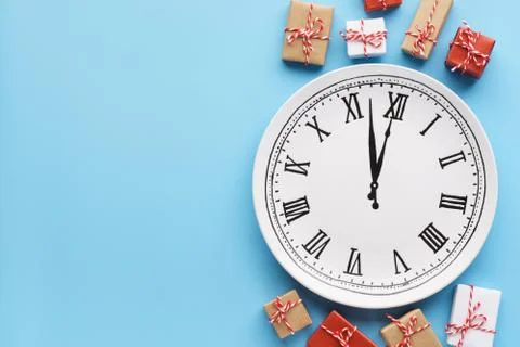 Gift boxes around a plate clock on light blue background. Stock Photos