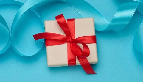Gift boxes in beige packaging with red satin bows and curly ribbons Stock Photos